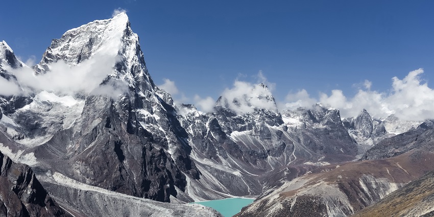 View of Nepal's Himalayas, with towering snow-covered peaks under a clear, bright blue sky