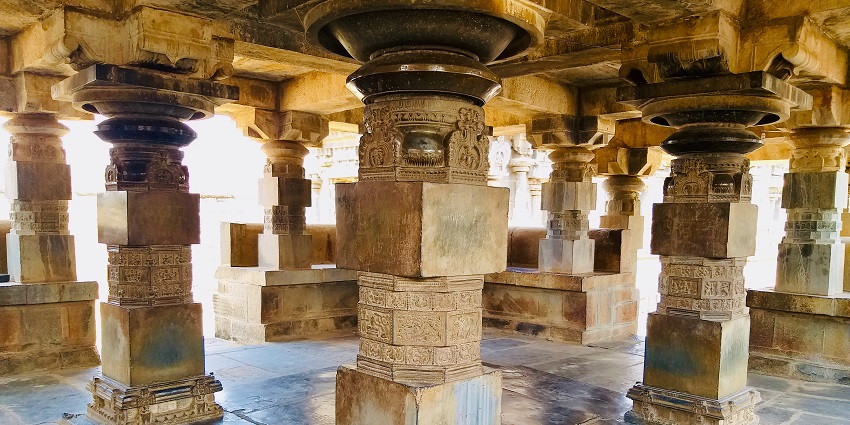View of temple pillars with detailed stonework, depicting scenes and showcasing the craftsmanship of the era