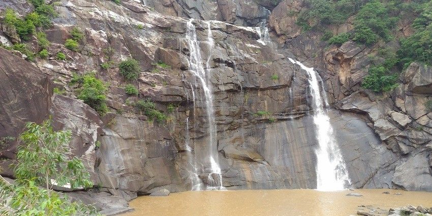 A stunning view of Netarhat Waterfalls cascading down rocky cliffs, surrounded by dense greenery