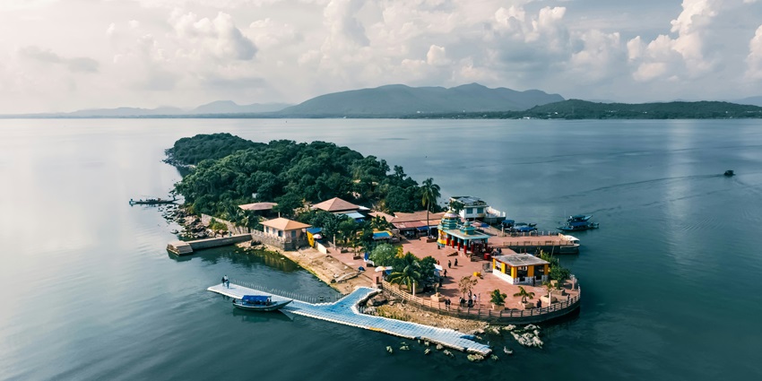 A breathtaking view of a lush green island with different houses and temples on it.