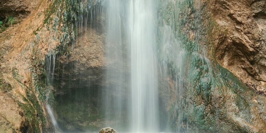 Bhagsunag waterfall cascading through rocky terrain surrounded by lush greenery, a place near Bhagsunag Temple