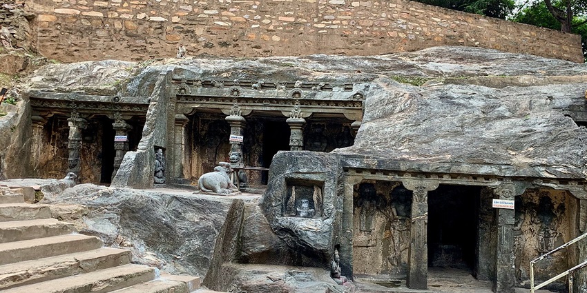 Ancient rock-cut Shiva temples nestled in Nallamala Hills with cascading waterfall and dense forest surroundings.