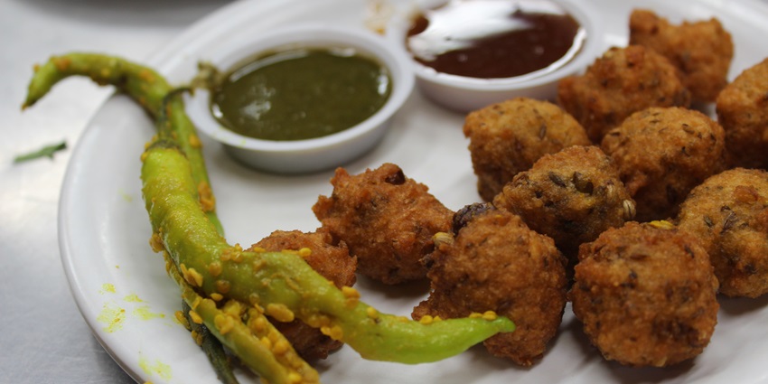 People have hot and crispy Bhajiya accompanied with tea as part of the tasty street food in Surat
