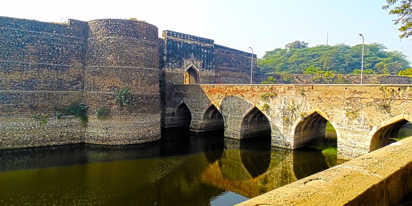 A picture of the enclosure walls of a fort in Bharatpur with a canal flowing in front of the entrance