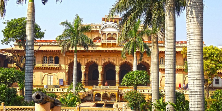 The grand Bharatpur Palace with intricate architecture, set amidst lush green surroundings.