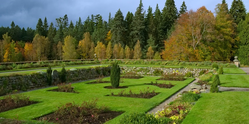 An image of a garden with lush lawns, vibrant flowers, and the castle in the distance.