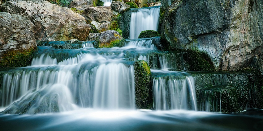 A scenic view of waters cascading through the rocky cliffs at the Bhimlat Waterfalls.