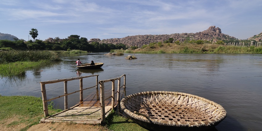 Traditional coracle boats floating on Tungabhadra river, surrounded by rocky landscapes