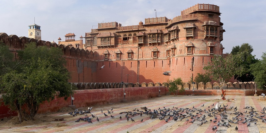 Historic red sandstone Junagarh Fort in Bikaner, Rajasthan, India, with pigeons nearby.