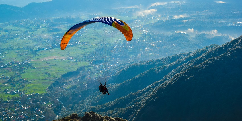 Image of Bir Billing in Himachal Pradesh a man paragliding over the lush green mountains