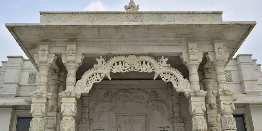 The image of the Birla Mandir under the clear blue sky and bustling with people.
