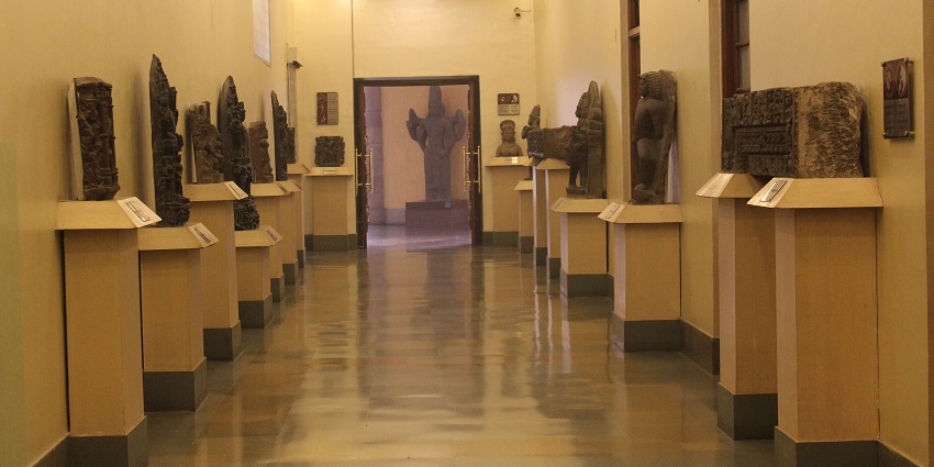 Multiple statues displayed in a museum room as artefacts and other historical documents