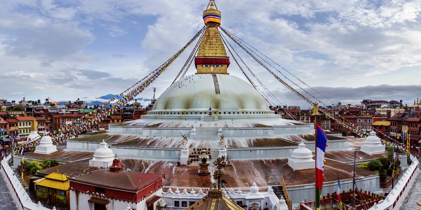 Boudhanath Stupa, a large spherical stupa in Kathmandu, Nepal, surrounded by blue sky.
