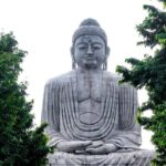 An image of the iconic Buddha Statue at a temple in Gaya, Bihar, with devotees gathered.