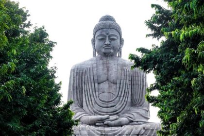 An image of the iconic Buddha Statue at a temple in Gaya, Bihar, with devotees gathered.