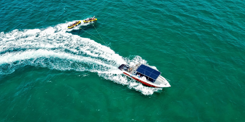 A top-down view of a speedboat pulling people sitting in inflated tubes in a sea