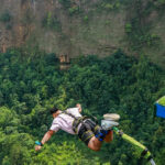 Image of a man bungee jumping in Manali with lush landscapes down the cliff