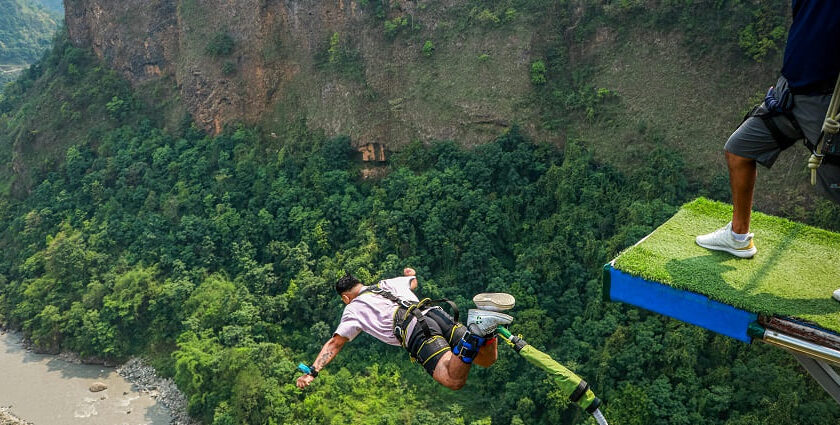 Image of a man bungee jumping in Manali with lush landscapes down the cliff