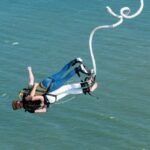 A person leaps off a platform into the air, experiencing the thrill of bungee jumping in Sentosa.