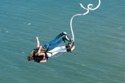 A person leaps off a platform into the air, experiencing the thrill of bungee jumping in Sentosa.