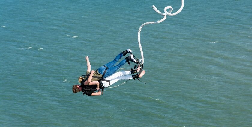 A person leaps off a platform into the air, experiencing the thrill of bungee jumping in Sentosa.