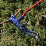 A breathtaking view of a man enjoying an adventure activity around lush greenery.