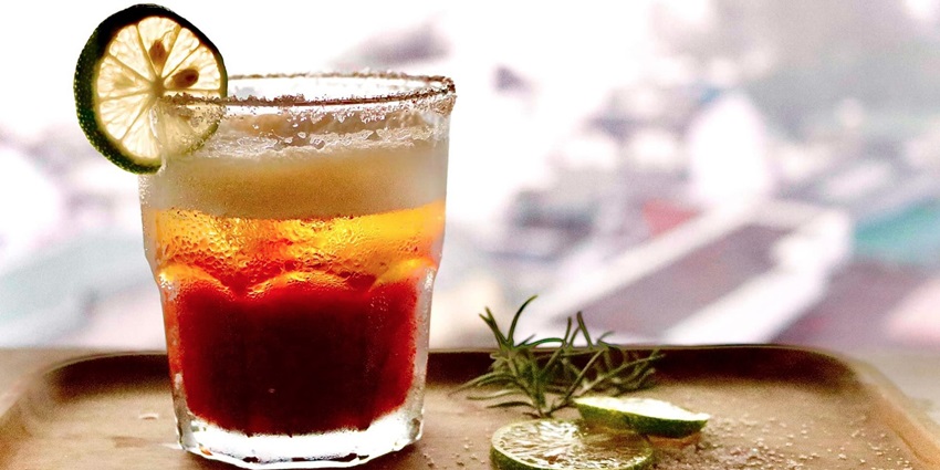 A mouth-watering view of a glass served with a colourful drink sitting on a table.