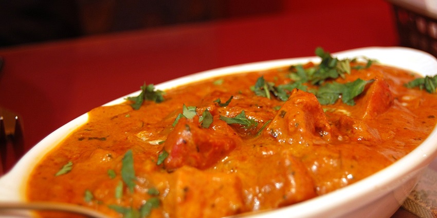 A mouth-watering view of a cooked gravy served on a plate sitting on a flat table.