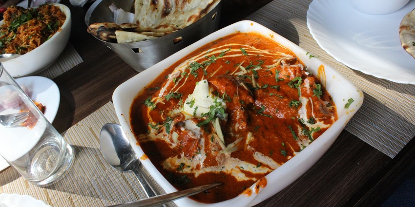 A big bowl of Creamy buttery Butter chicken with Hot Garlic Naans and paratha