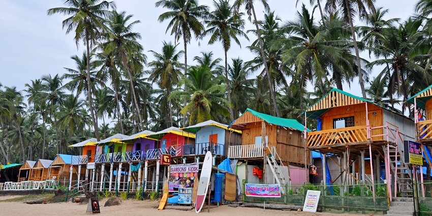Little colorful cottages aligning the shores of the beach with tall palms standing behind them
