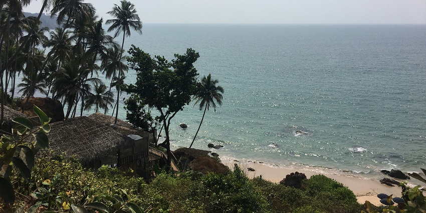 An enchanting vista of Cabo De Rama Beach featuring shimmering waters and tall trees.