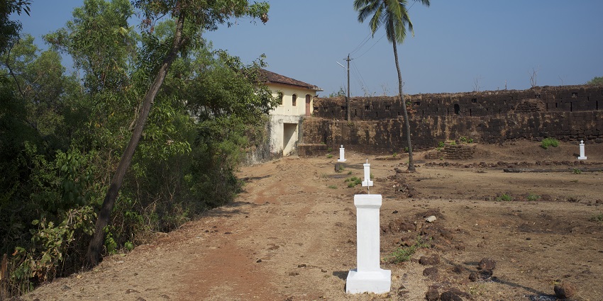 Cabo de rama fort standing amidst the sandy fields surrounded by tall palm trees