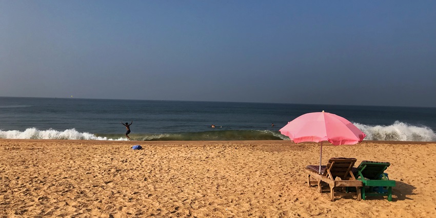 Bustling Calangute Beach with golden sand, waves, and tourists enjoying water sports.