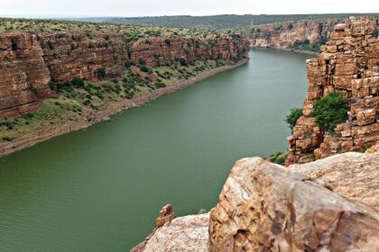 Body of water nestled between rocky cliffs with a clear blue sky - Camping in Gandikota