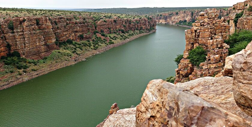 Body of water nestled between rocky cliffs with a clear blue sky - Camping in Gandikota