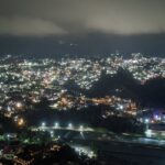 A night view of Solan with illuminated buildings nestled among the hills under a starry sky.