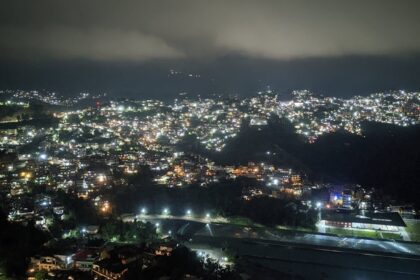 A night view of Solan with illuminated buildings nestled among the hills under a starry sky.