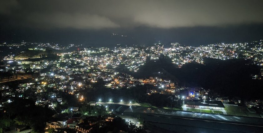 A night view of Solan with illuminated buildings nestled among the hills under a starry sky.