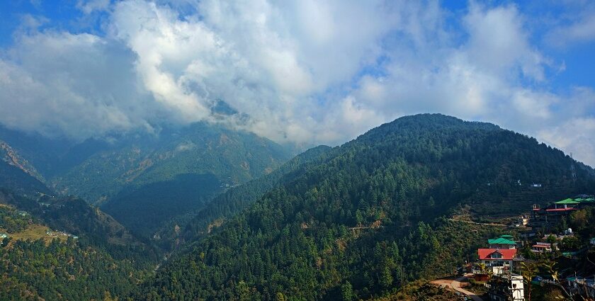 A scenic valley with lush greenery, framed by towering mountains under a bright blue sky