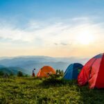 A breathtaking view of dome-shaped camps on a lush green mountain range during the day.