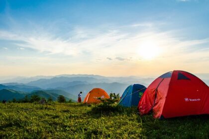 A breathtaking view of dome-shaped camps on a lush green mountain range during the day.