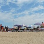 A picture of a beach with people enjoying under umbrellas to save from heat