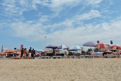 A picture of a beach with people enjoying under umbrellas to save from heat