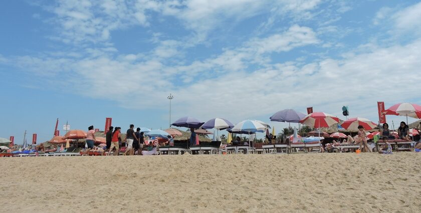 A picture of a beach with people enjoying under umbrellas to save from heat