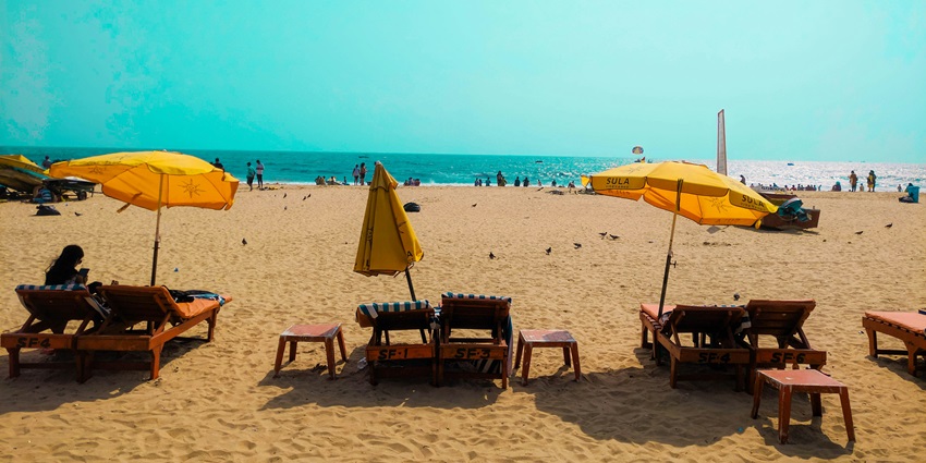 A view of chairs on the golden shorelines of Baga Beach surrounded by azure waters.
