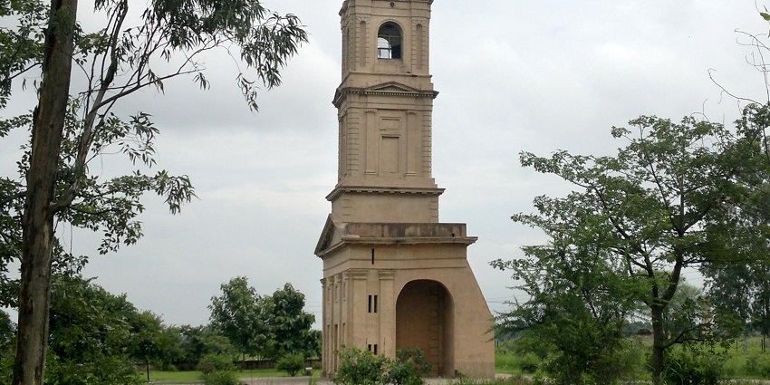 View of the church tower surrounded by lush greneery against the clear blue sky
