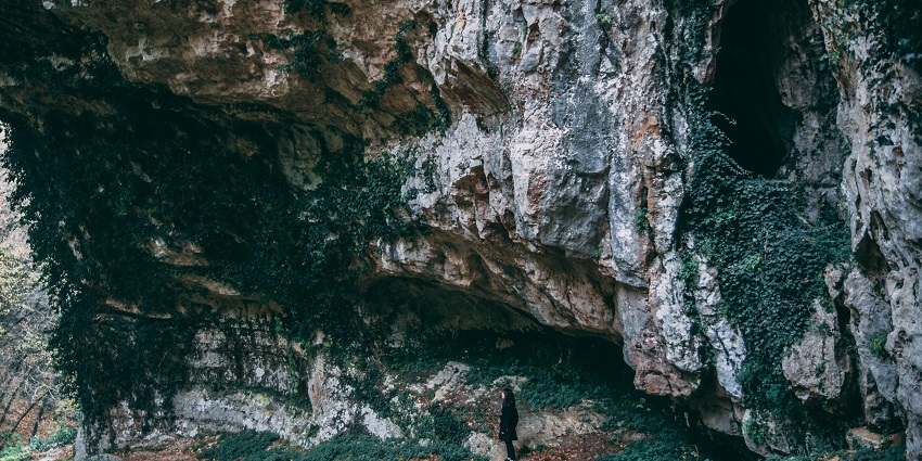 An image of explorers inside a cave showcasing ancient rock formations.