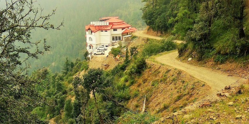 A mesmerising view of Chail surrounded by lush greenery and mountains during the day.