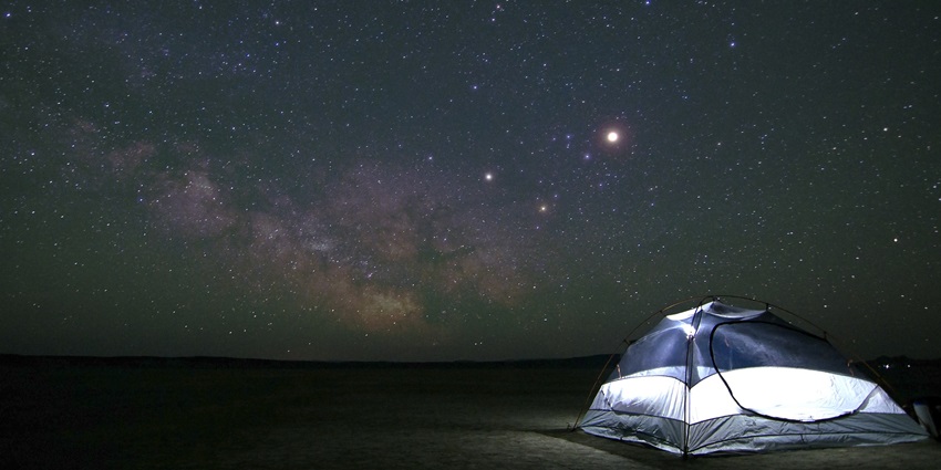 A tent under a clear night sky filled with stars and constellations for camping in Solan.