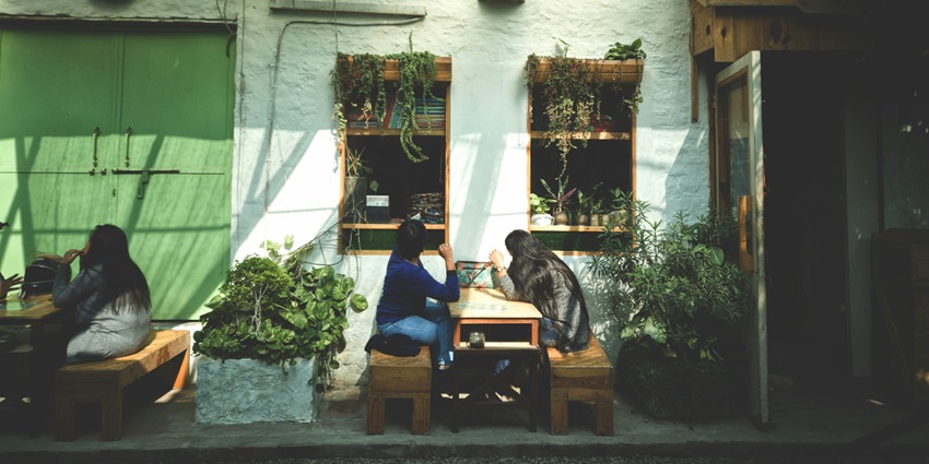An image of people enjoying coffee outside of a cafe with aesthetic sitting arrangement